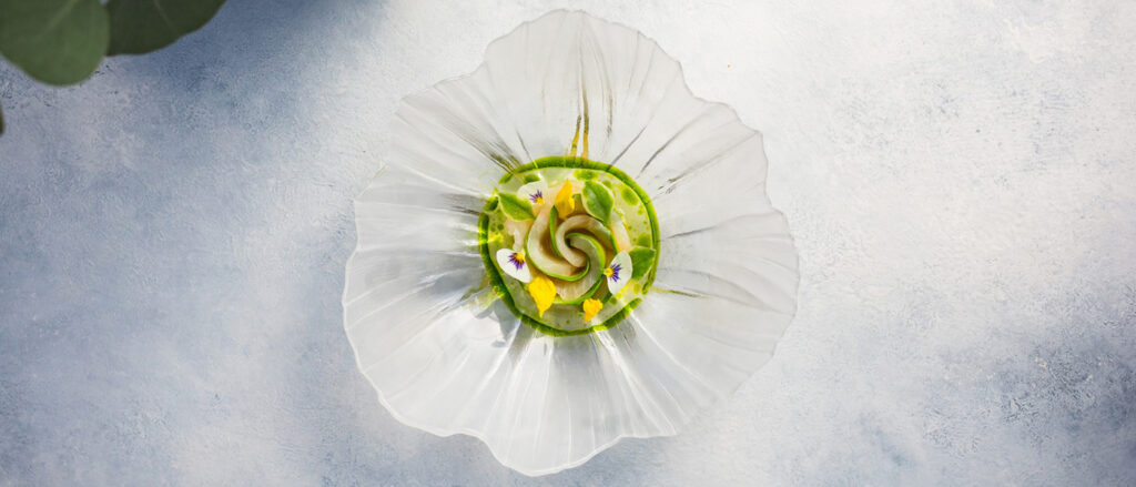 Green and yellow dish plated on an organic-edged glass plate