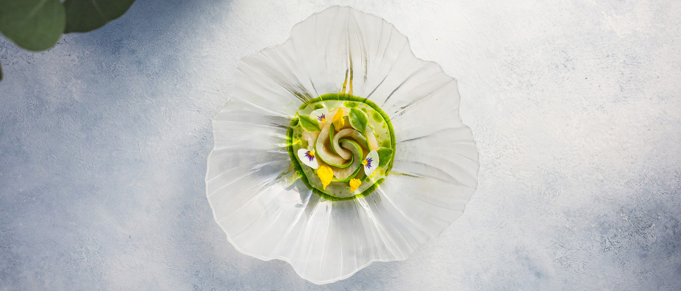 Green and yellow dish plated on an organic-edged glass plate