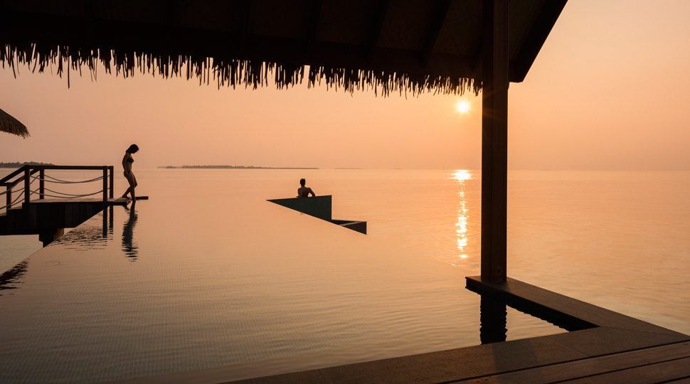 A couple enjoys the infinity pool at Four Seasons Maldives Private Island at Voavah.