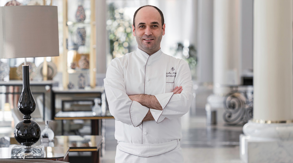 Talha Barkin, Executive Chef, Four Seasons Hotel Baku, smiles in an ornate restaurant dining room