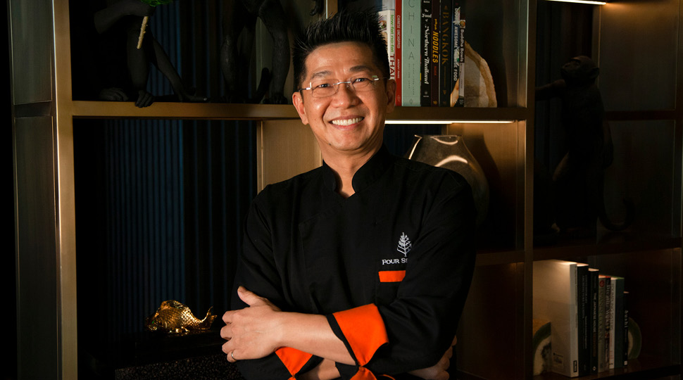 Leong Then, Asian Chef de Cuisine, Far & EastFour Seasons Hotel Bengaluru at Embassy ONE, smiles in front of a modern bookshelf
