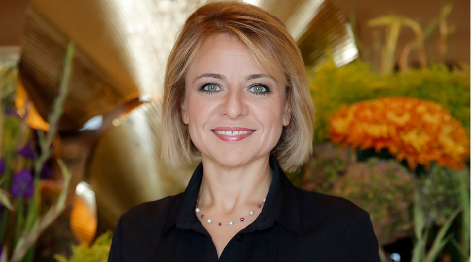 Serap Akkuş, Senior Food & Beverage Director, Four Seasons Hotel Istanbul at the Bosphorus and Four Seasons Hotel Istanbul at Sultanahmet, smiles in front of colorful floral arrangements