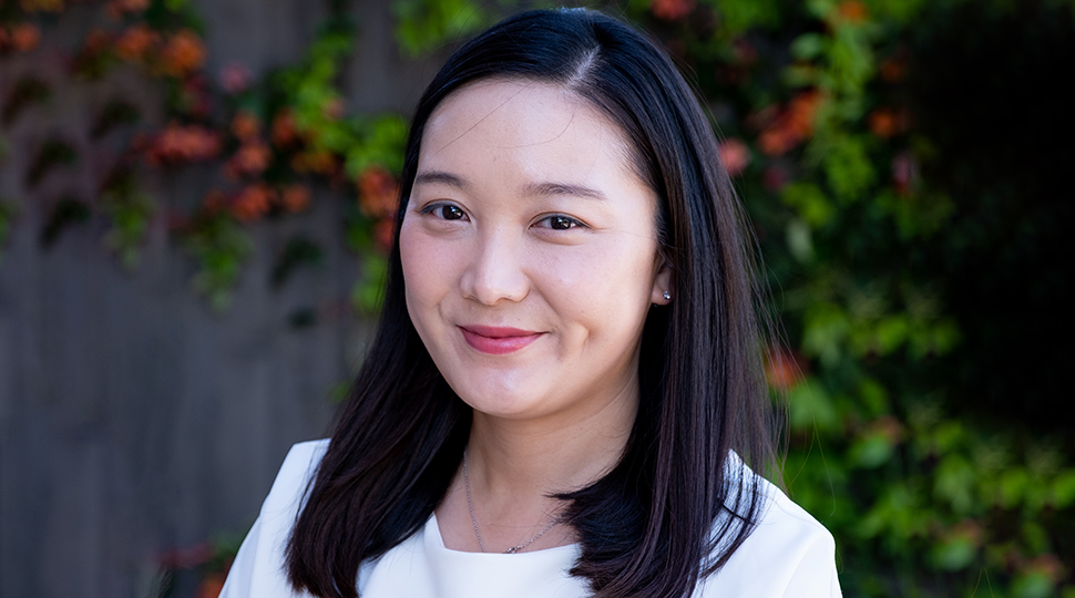 Jane Kim, Resort Manager, Four Seasons Resort and Residences Napa Valley, smiles in front of a wall covered in greenery