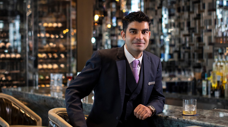 Ashish Sharma, Head Bartender, Four Seasons Hotel Kuala Lumpur, poses while sitting at a modern bar