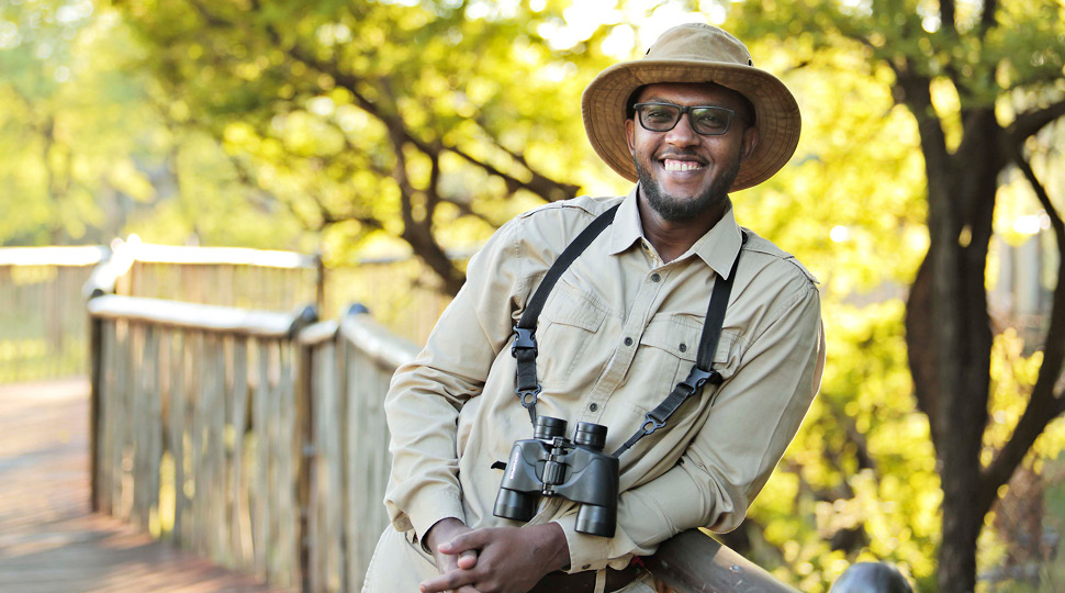 Ahmed Attas, Discovery Centre Manager smiles, surrounded by green trees
