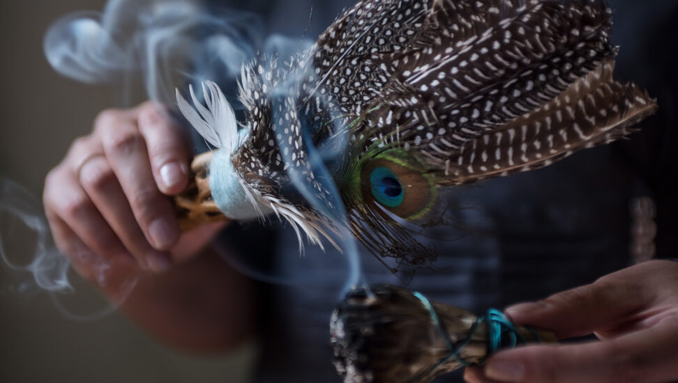 Close-up of smoke rising from sage, feathers used for smudging ceremony
