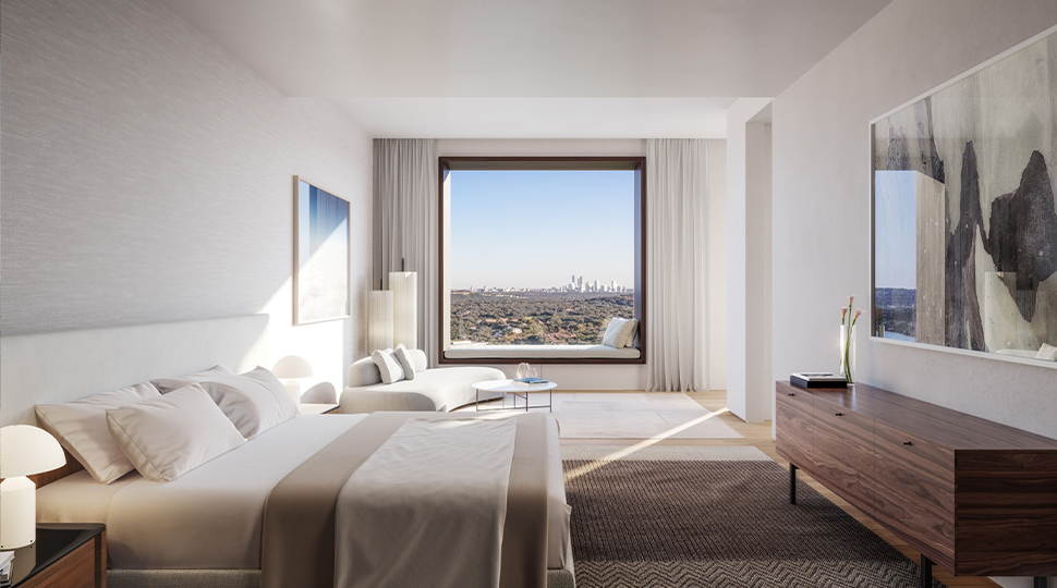 Bed with neutral linens in front of a square picture window