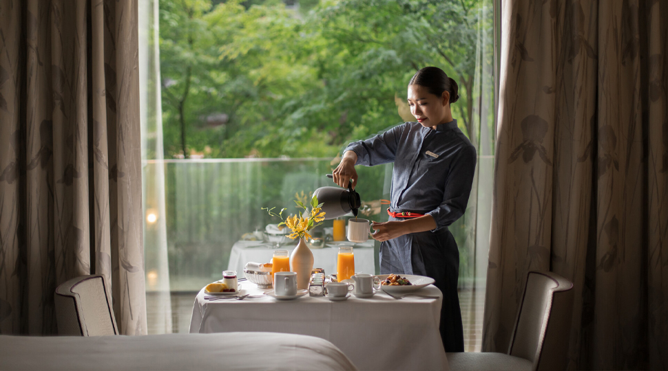 Waitress pouring coffee into a mug at a table set for afternoon tea
