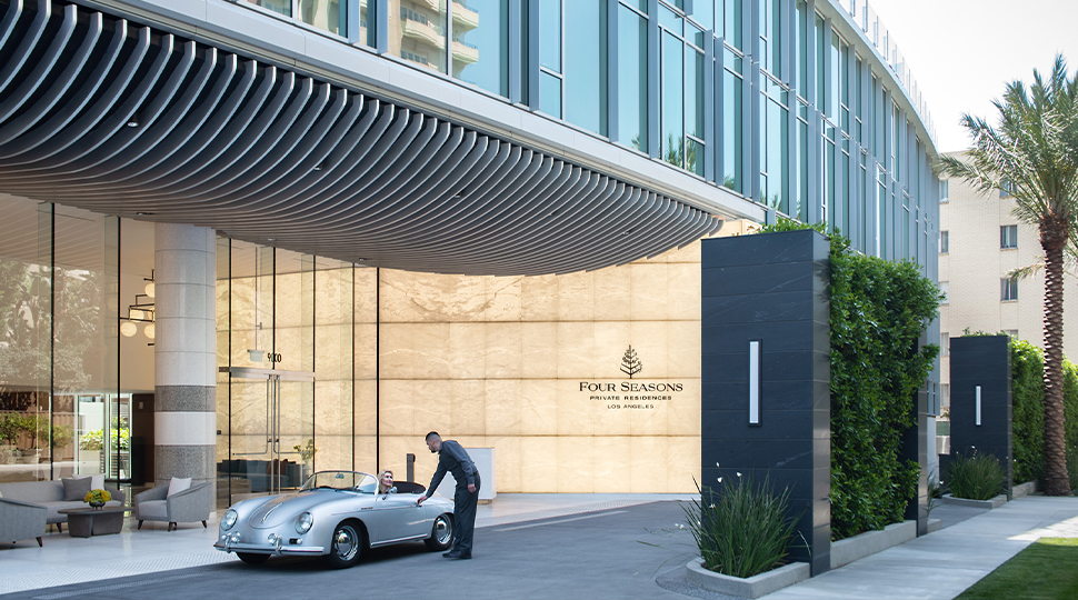 Valet comes up to a silver sports car at the entrance of Four Seasons Private Residences Los Angeles
