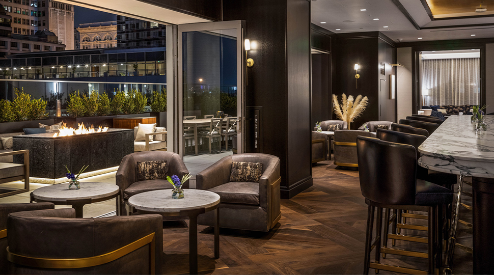 Lounge with marble bar, small table with club chairs and doors leading out to an outdoor terrace
