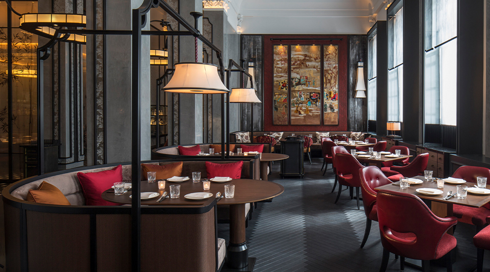 Interior of Mei Ume restaurant in London with dark grey walls and flooring, large windows, brown wooden tables and red dining chairs
