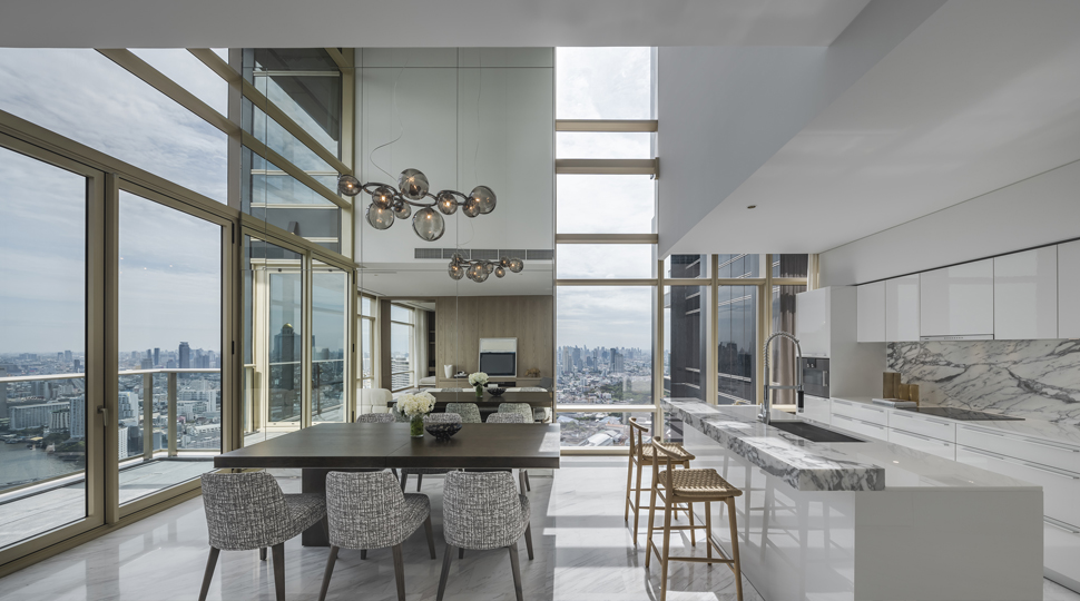 Open-concept kitchen and dining area with double-height ceilings and floor-to-ceiling windows