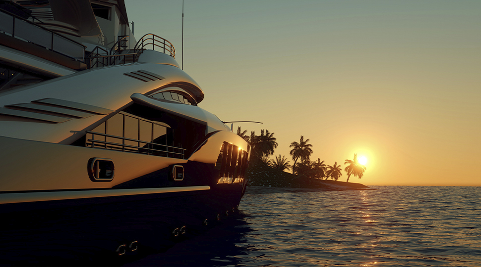 Side of a private boat docked by a palm-tree ringed island at sunset