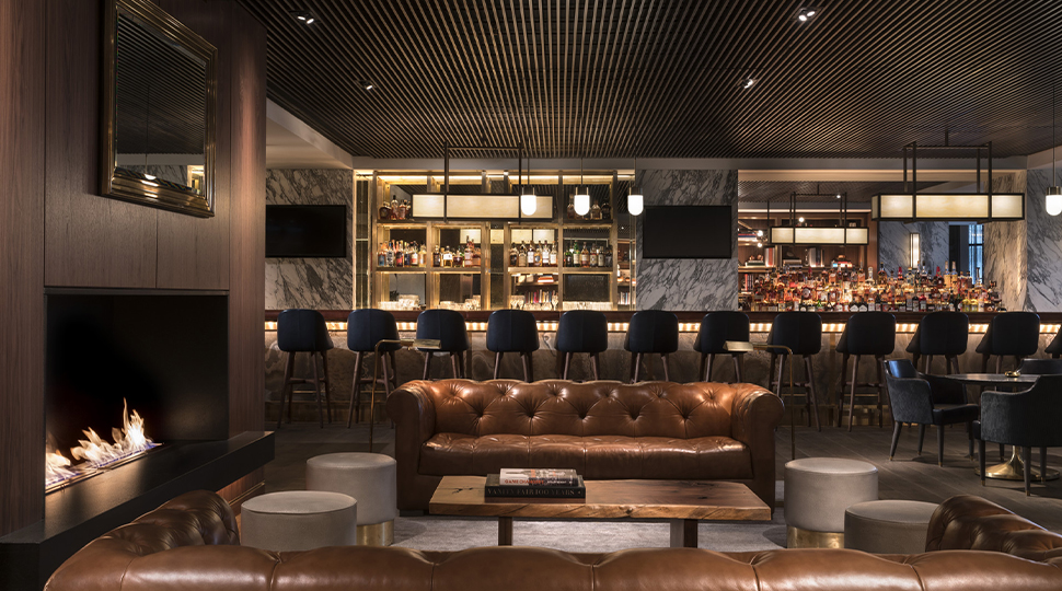 Dimly lit bar with brown tufted leather couch in the centre
