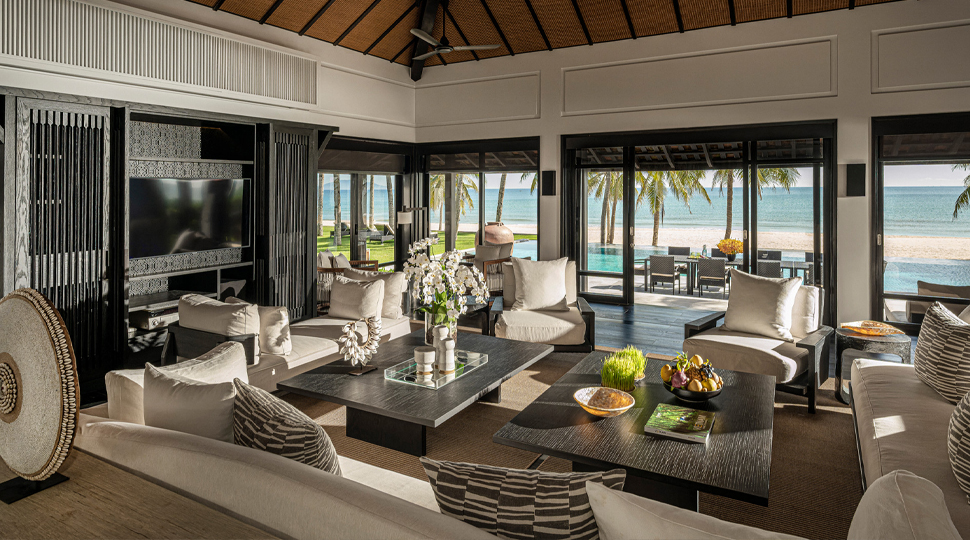Large living room with the beach in the distance seen through the sliding-glass doors