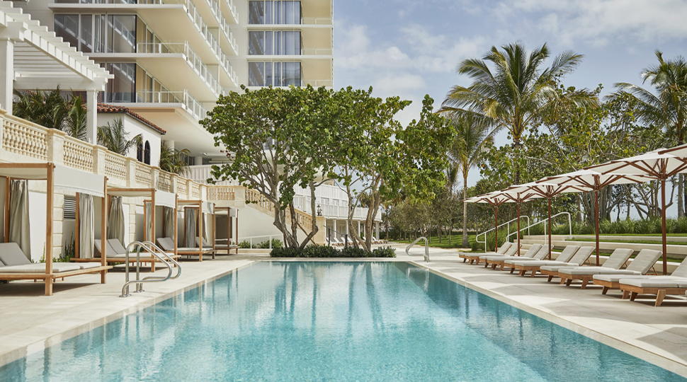 Outdoor hotel pool surrounded by cabanas and lounge chairs