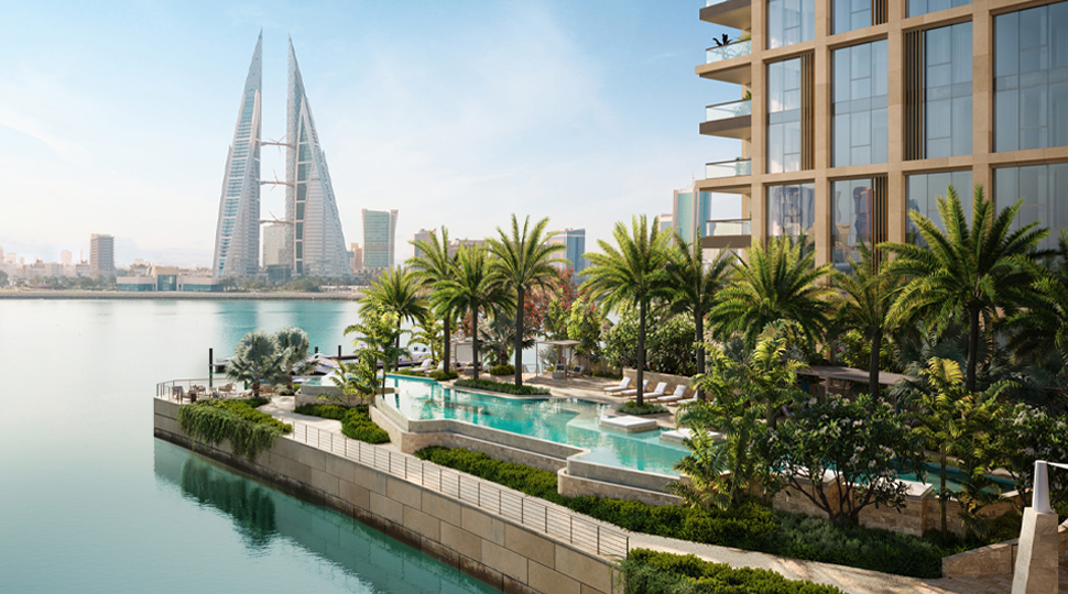 Outdoor pool sits on a ledge next to the water with a city skyline in the background