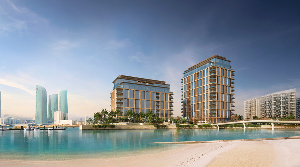 Two residential buildings sit across a bridge from a beach